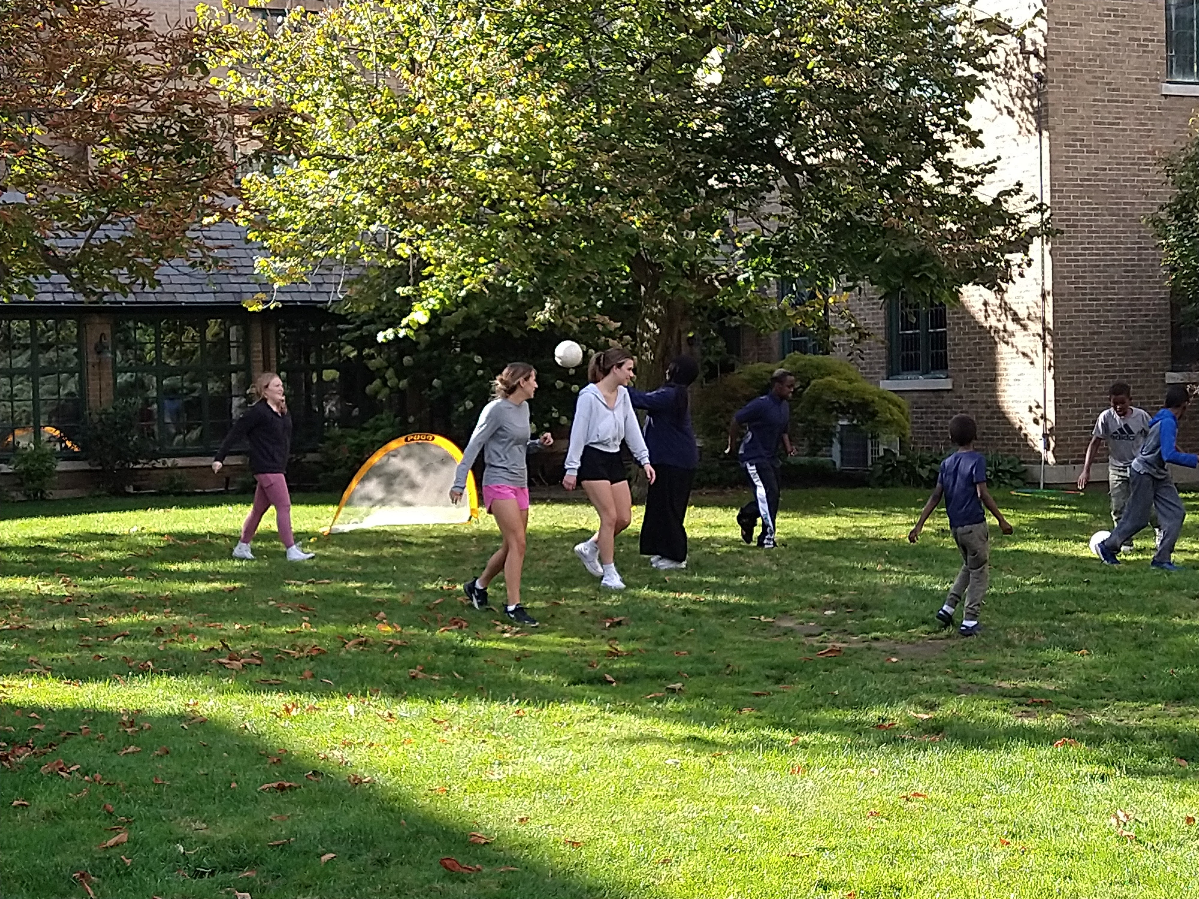 Three college students play soccer with five junior high school students