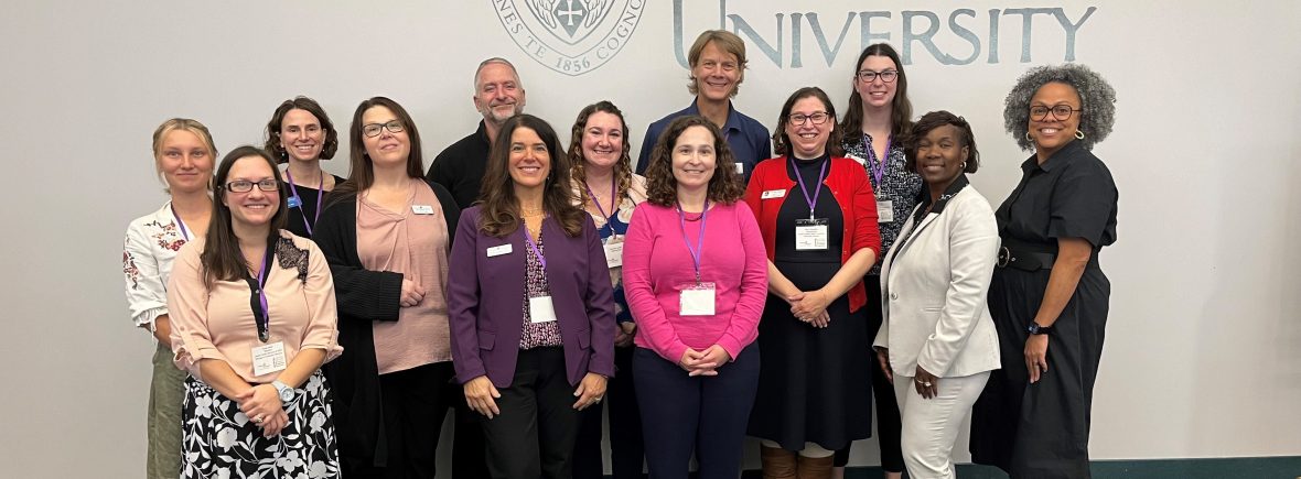 2024 Steering Committee with Plenary Speaker, Danielle Battle, in front of Niagara University logo.